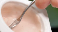 Spoon in cup stirring yogurt