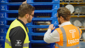 Image of an Avery Dennison employee and a Tosca employee examining reusable plastic pallets.